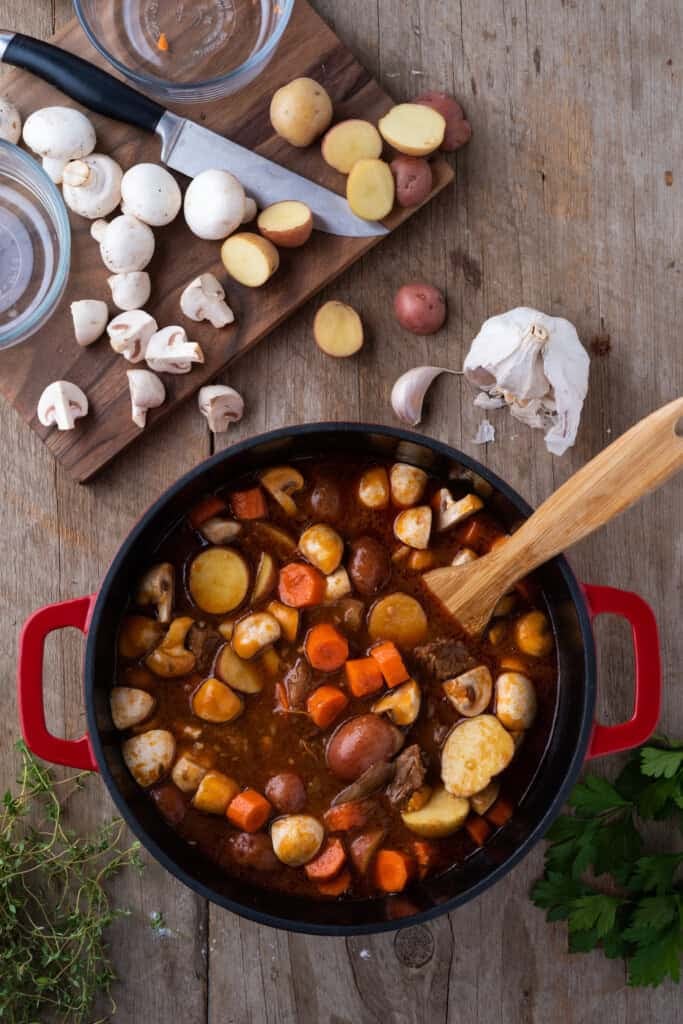 Overhead view of vegetables stirred into beef stew.