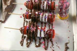 Closeup of drizzled chocolate and sprinkles over the strawberry, brownie, marshmallow kabobs.