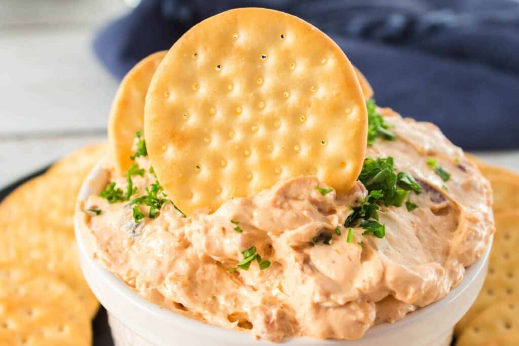 Chicken Spread in a bowl with crackers on top.