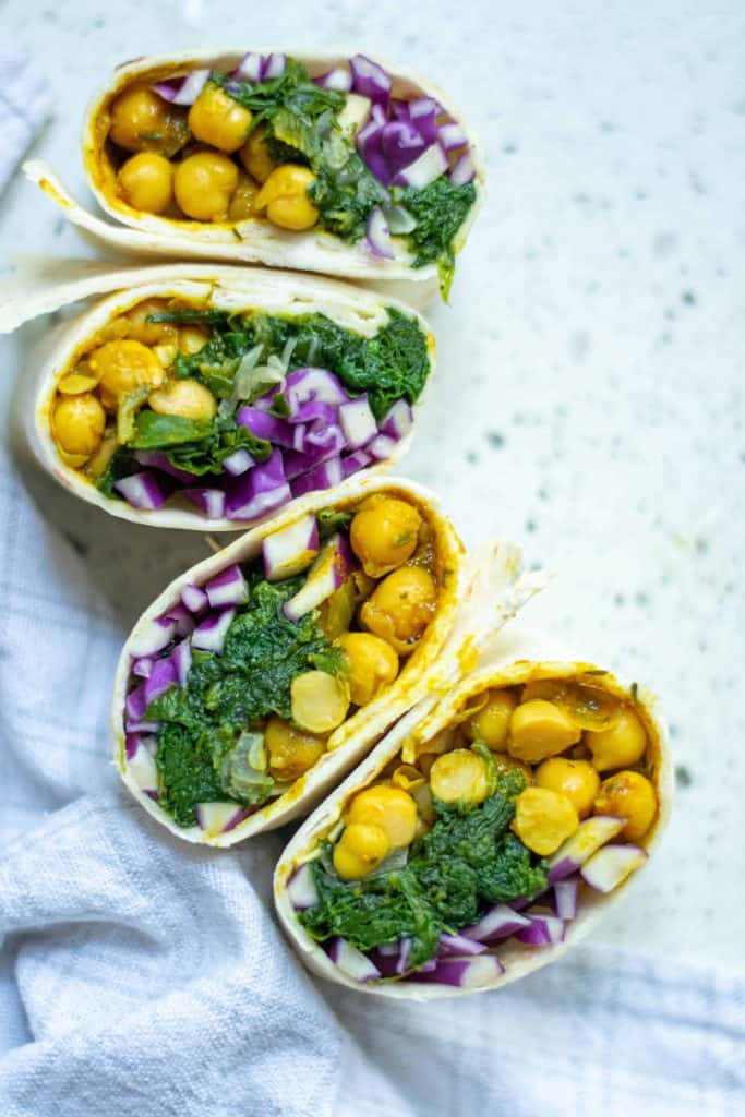 4 Curried chickpea wrap halves on a white marble backgorund.