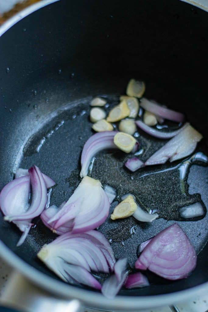 Sliced red onion and garlic in a sauté pan with olive oil