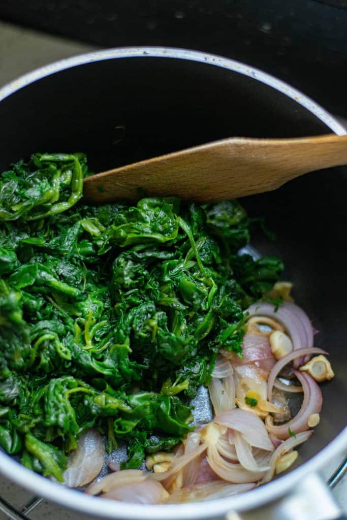 Spinach bin a sauce pan with red onion and garlic.