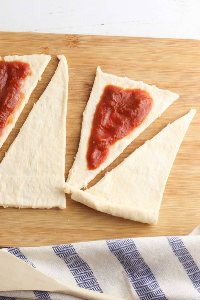 Pizza sauce spread on top of crescent roll dough.