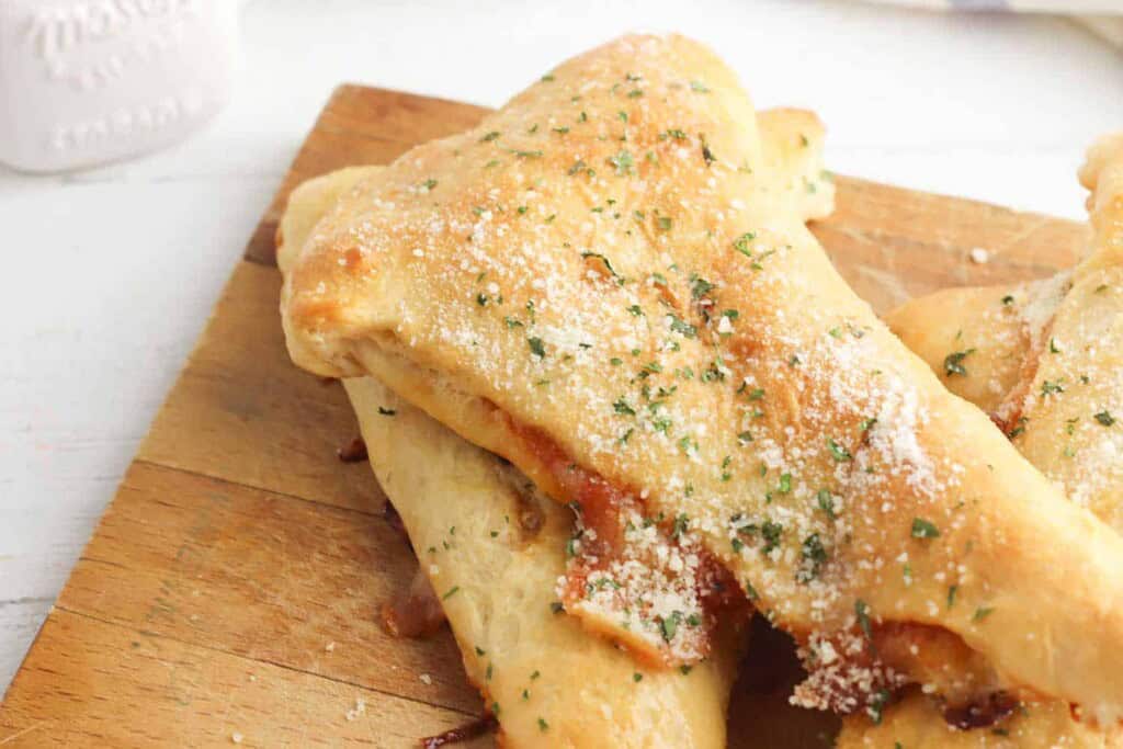 Close up of pepperoni and cheese calzones on a cutting board.