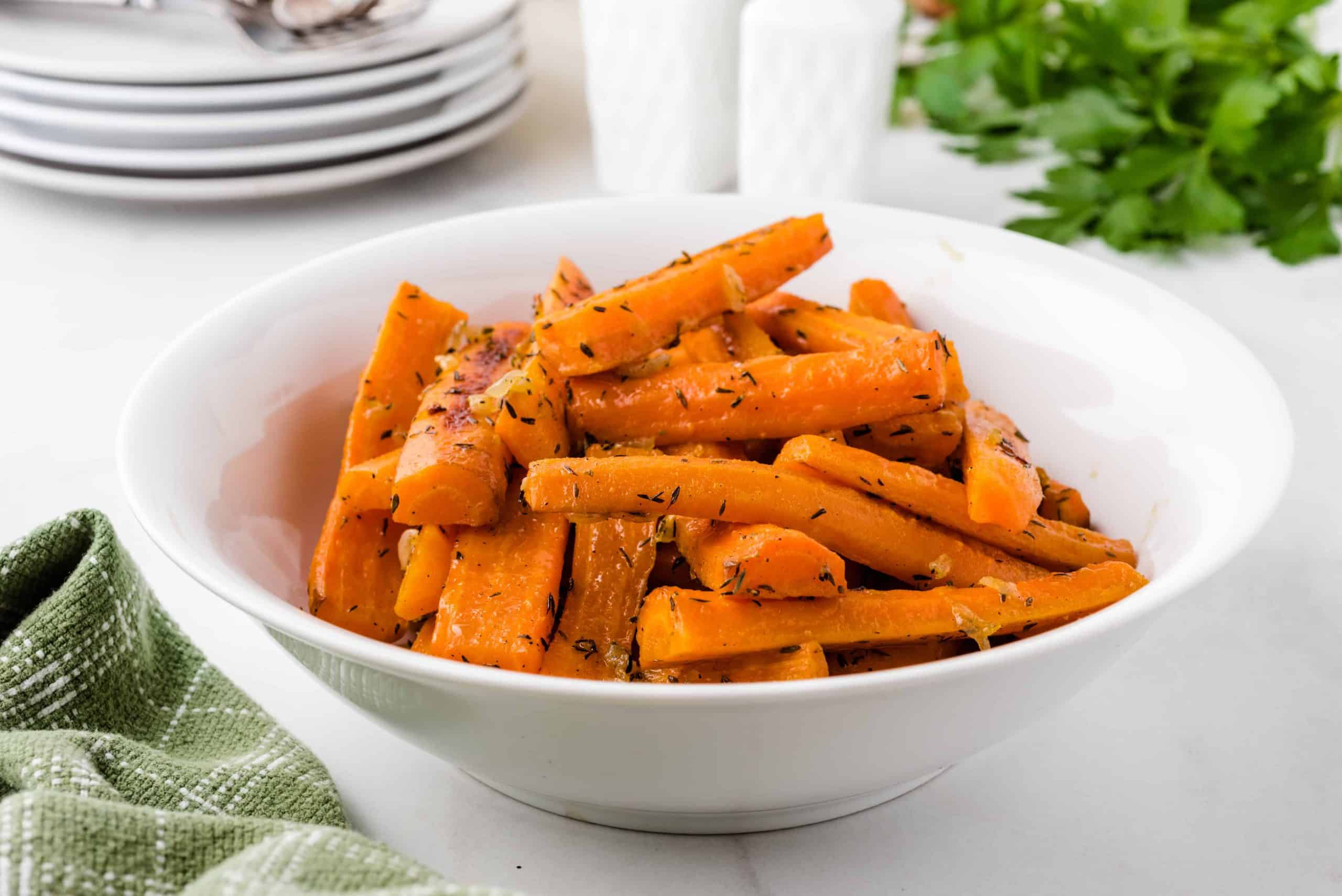 Oven baked carrots with herbs in a white bowl.