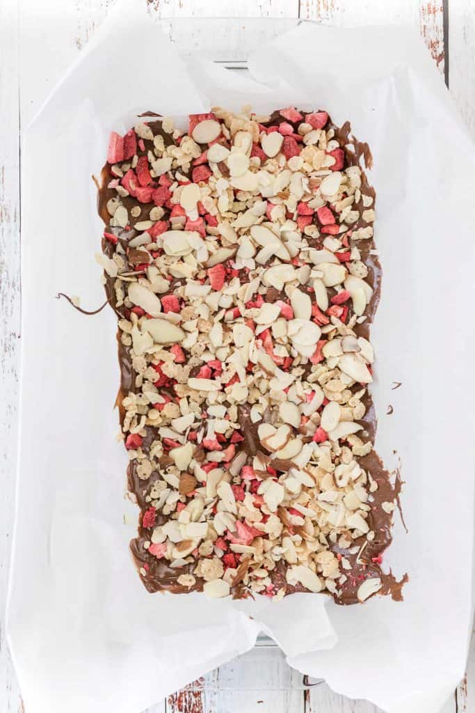 chocolate bark with almonds and sprinkles on parchment paper.