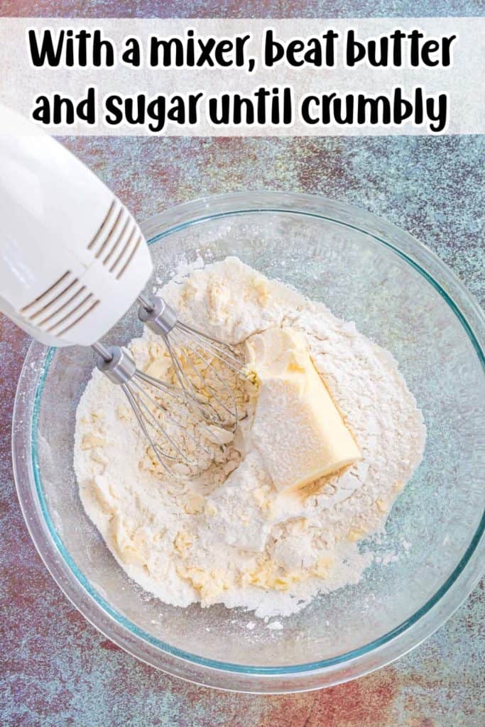 Flour and butter in glass bowl with blender beating ingredients together.
