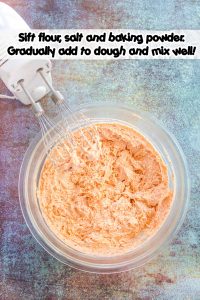 Carrot Cookie dough in a glass bowl with mixer in the bowl.