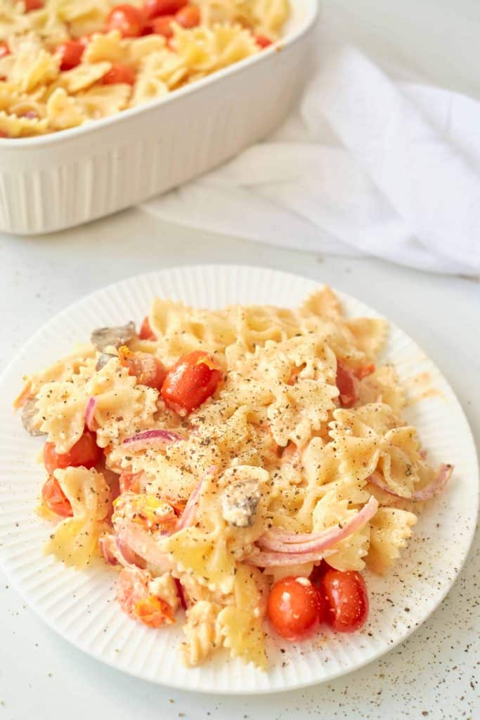 Bow tie pasta with cherry tomatoes on a white plate.