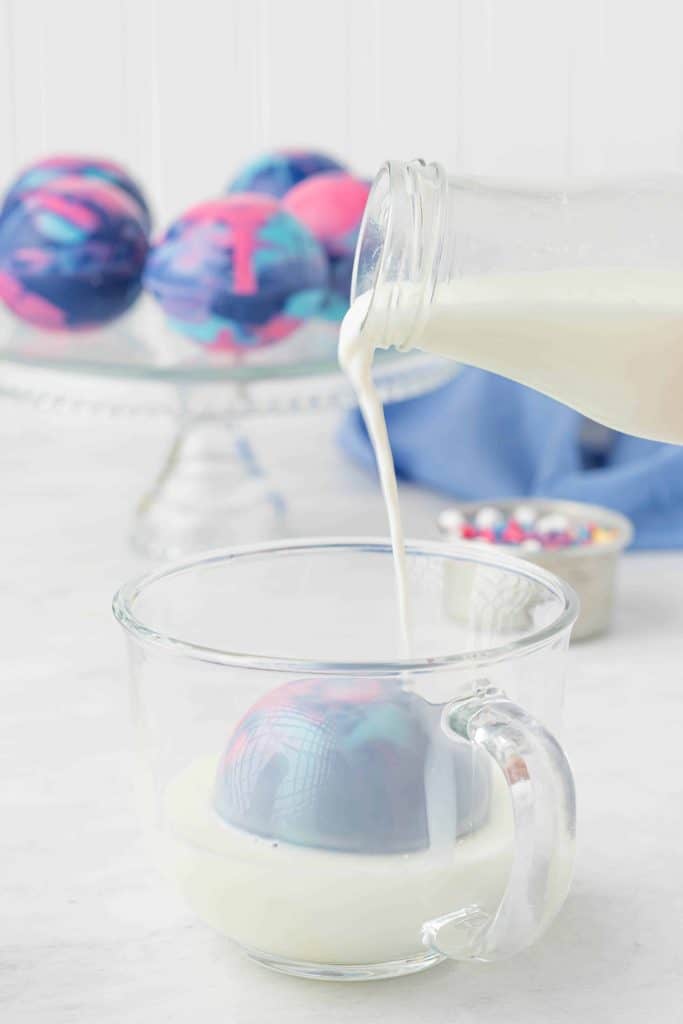 Hot milk being poured on top of Galaxy Hot Cocoa Bomb