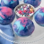 &frac34; angle view of galaxy hot cocoa bombs on a glass cake stand.