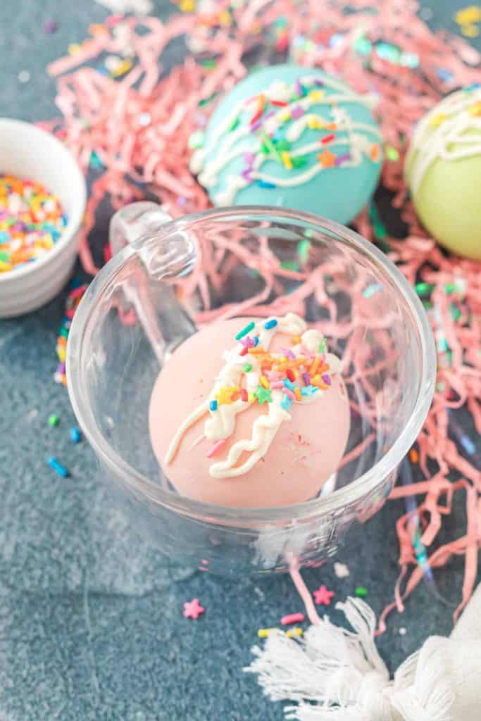 Pink hot cocoa bomb in a glass mug.