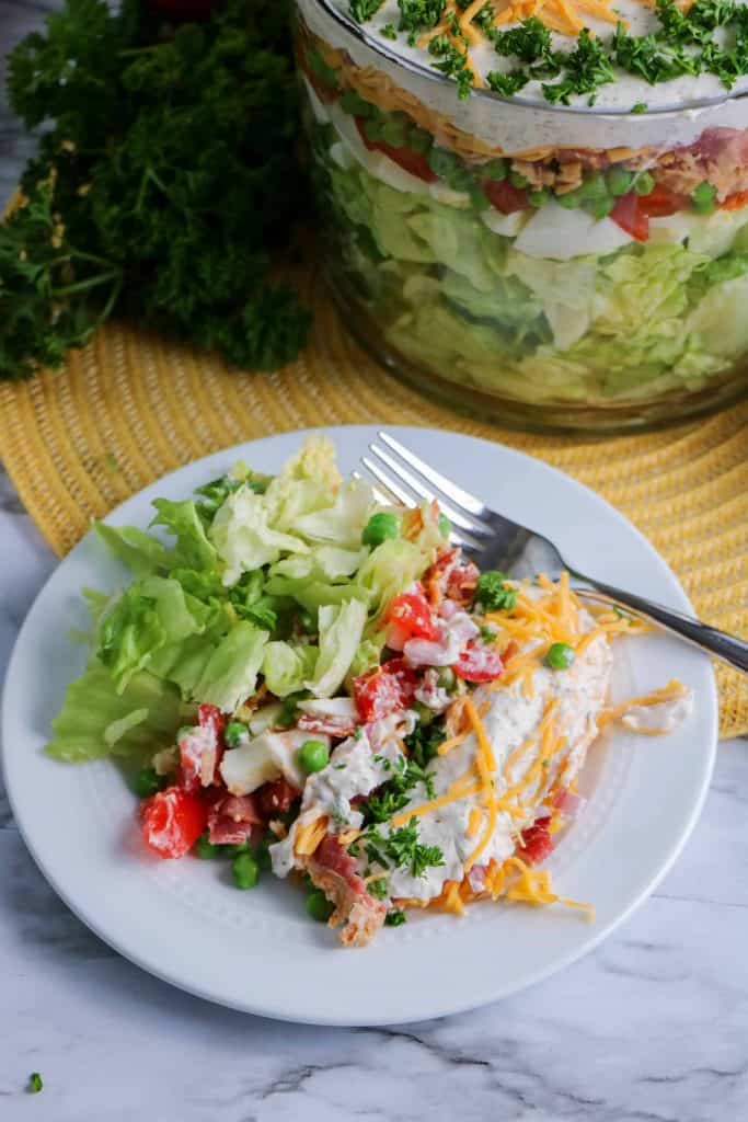 Layered salad served on a plate with truffle bowl of it in the background.
