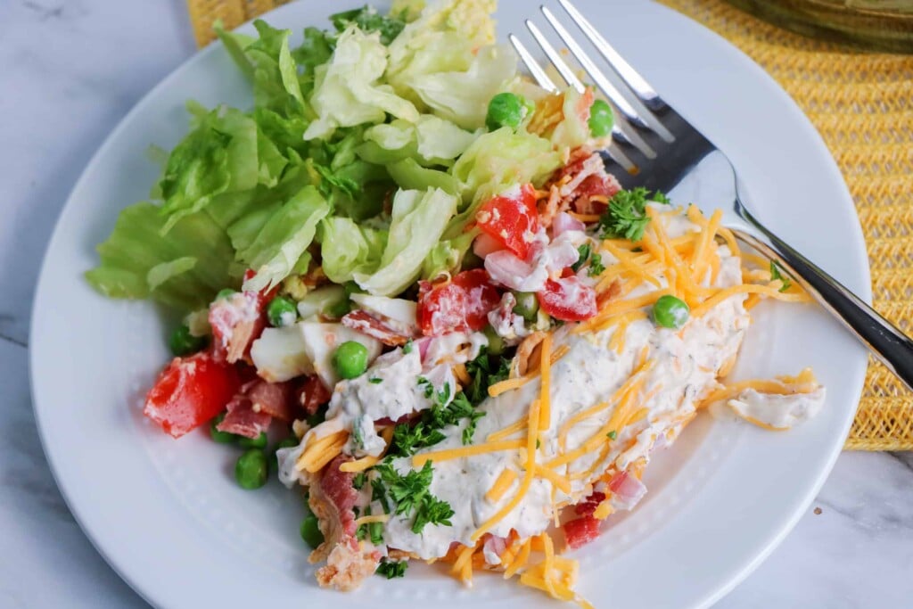 Overhead view of salad on a white plate with a fork on the side.