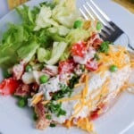 Overhead view of salad on a white plate with a fork on the side.