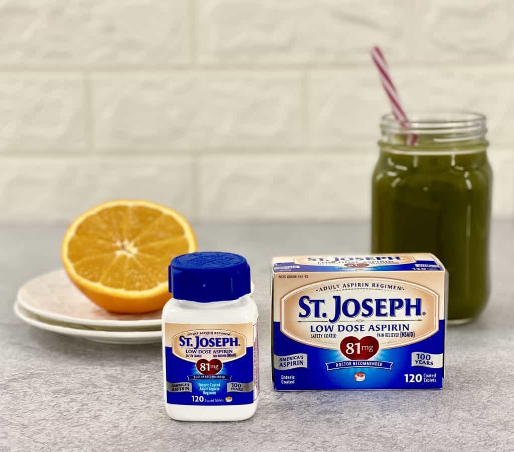 St. Josehph's low dose aspiring on a stone countertop with a green smoothie and half an orange in the background.
