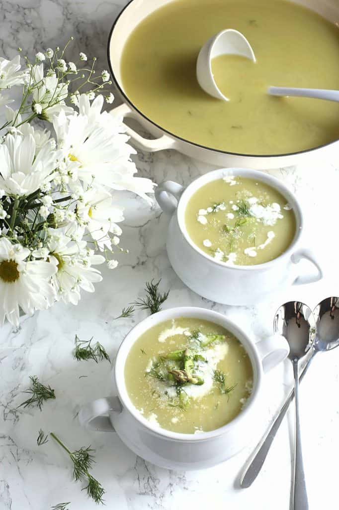 2 bowls of soup with a pot of it with a ladle in it in the back.