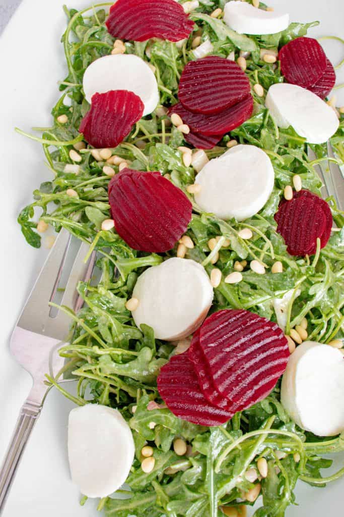 Beet slices and mozzarella slices on top of arugula