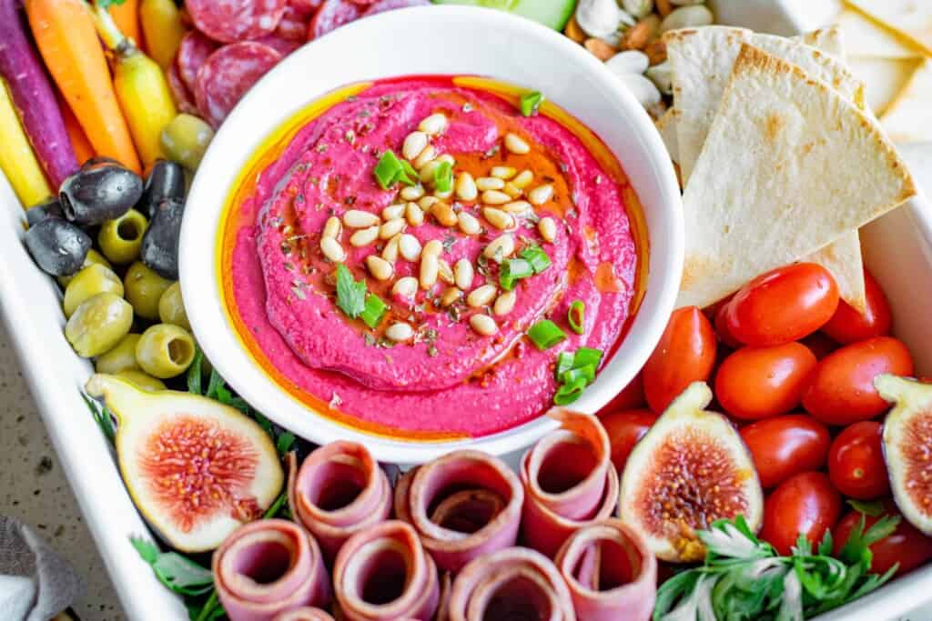 Roasted beet hummus in the center of a charcuterie platter.