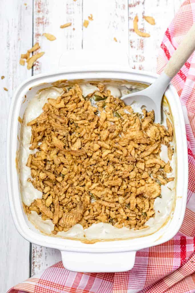 Overhead view of green bean casserole in a white baking dish with a spoon in it.