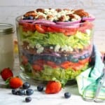 Head-on view of blueberry strawberry salad and buttermilk dressing in a Mason Jar on the side.