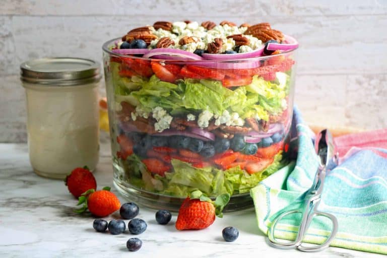 Head-on view of blueberry strawberry salad and buttermilk dressing in a Mason Jar on the side.