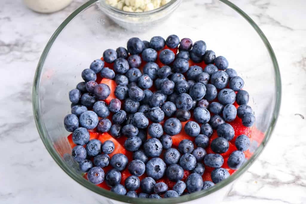 Blueberries on top of strawberries in a trifle bowl.