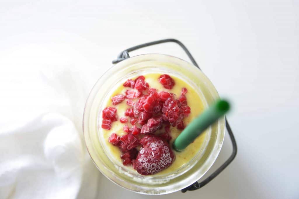 Overhead view of drink with a green straw in it.