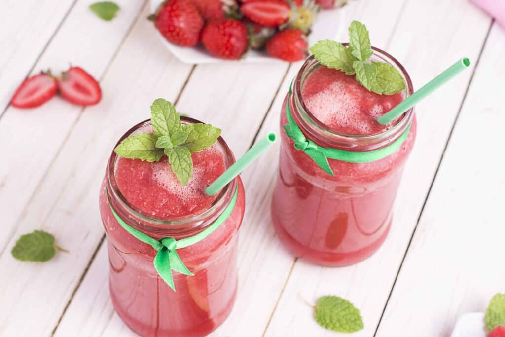 &frac34; angle view of 2 strawberry smoothies with fresh mint garnish.