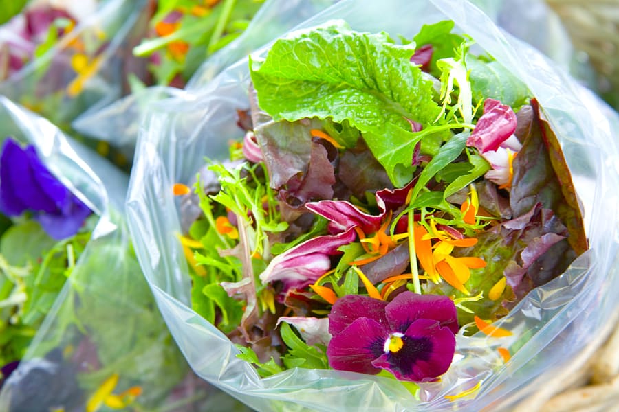 Spring salad mix with edible flowers in a plastic bag.