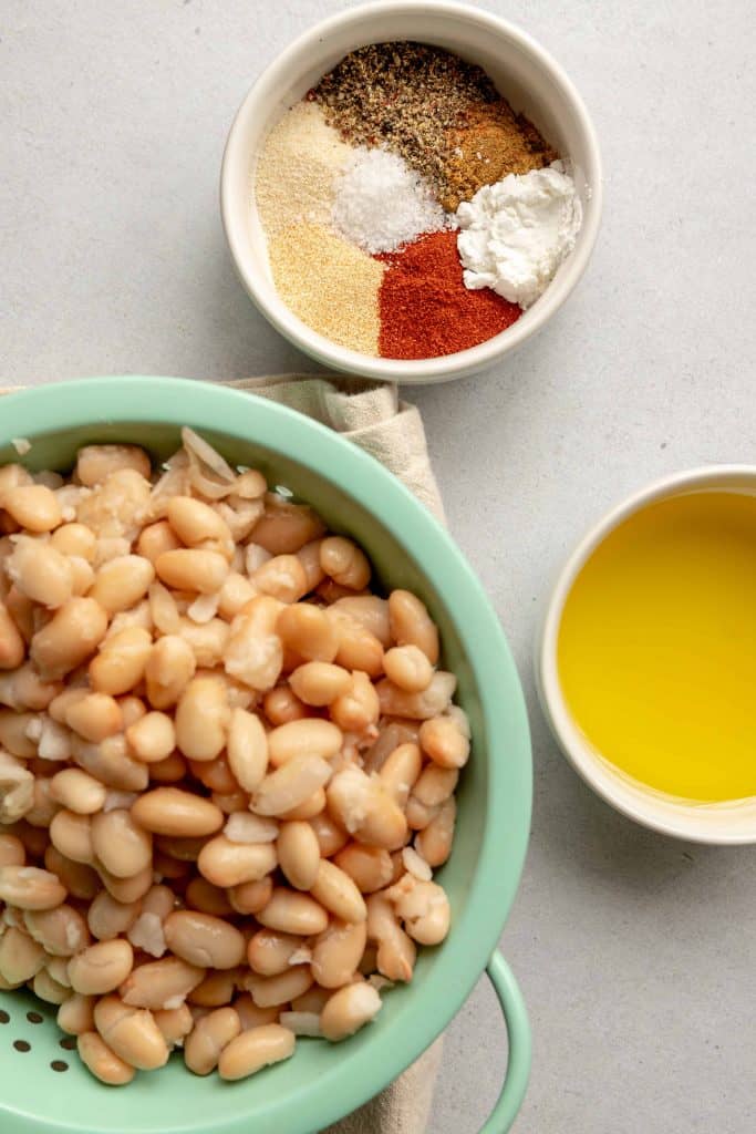 Overhead view of white beans, spices and olive oil.