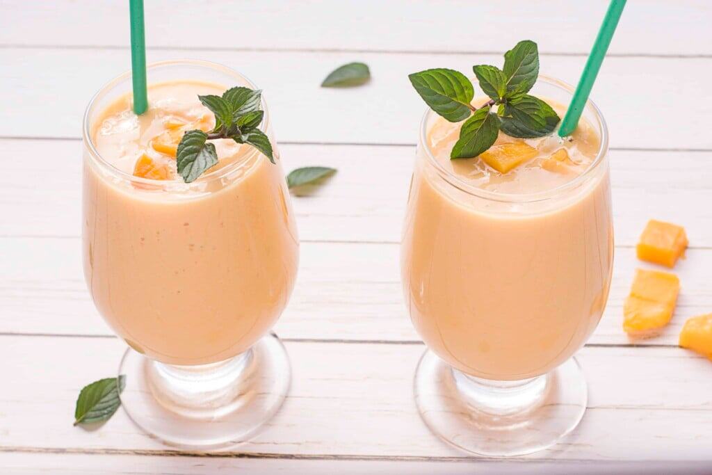 Too Mango Lassis side by side on a white wood background.