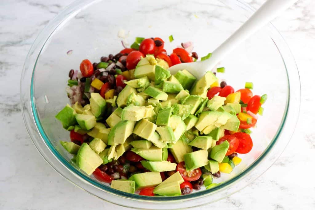 Diced avocado on top of black beans and cherry tomatoes.