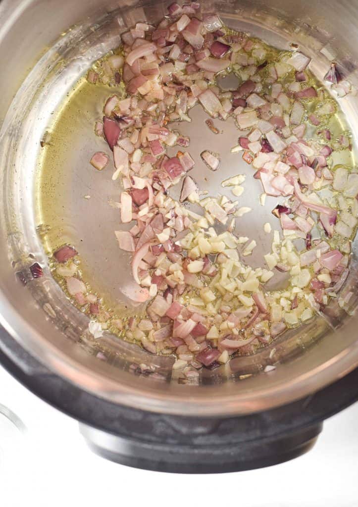 Diced red onion and garlic in the bottom of the Instant Pot.