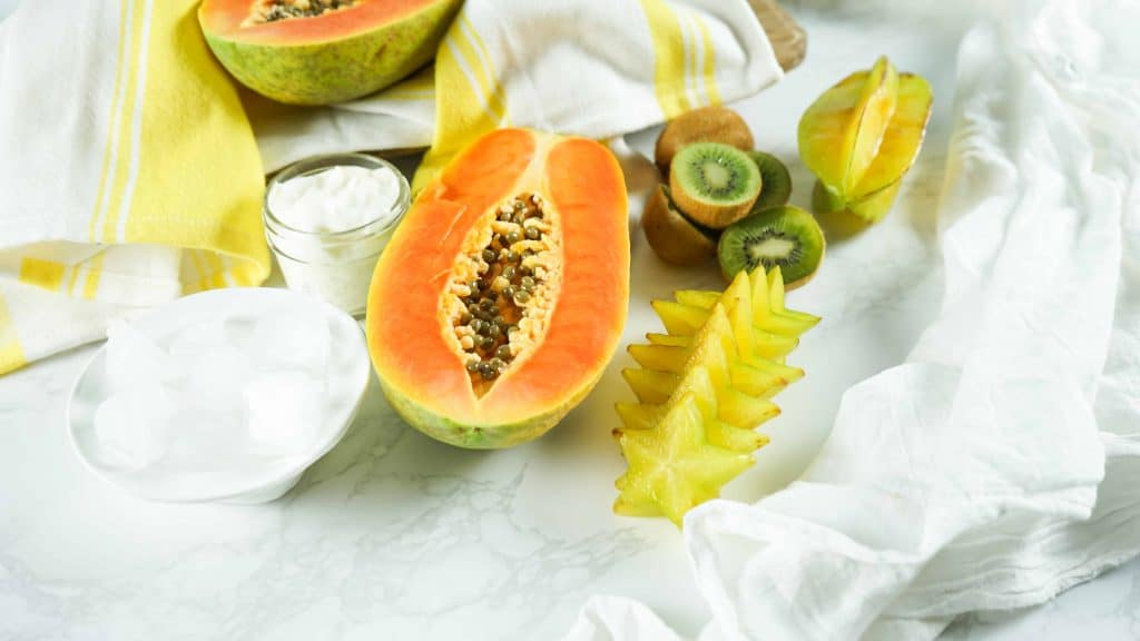Papaya, Kiwi, Starfruit, Ice and Yogurt on a white background.