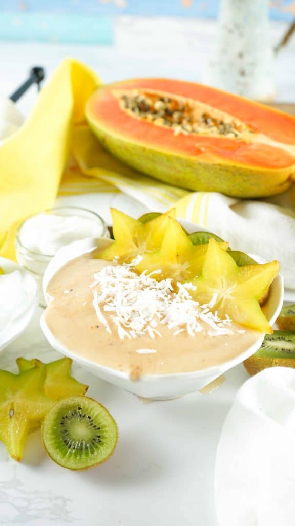 Tropical Smoothie Bowl with Papaya sliced in half in the background.