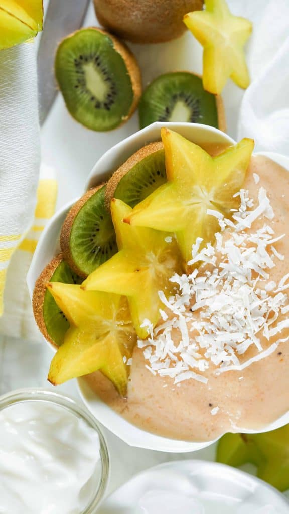 Overhead view of tropical smoothie bowl with starfruit, kiwi and coconut sprinkled on top.