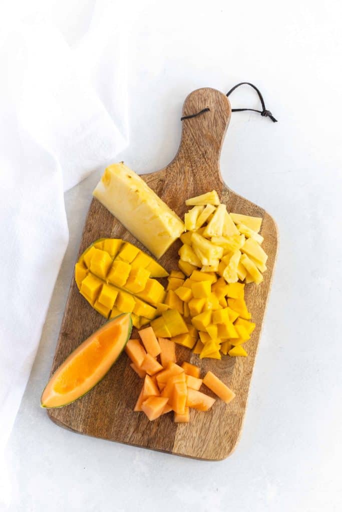 Mango, pineapple and cantaloupe on a cutting board.