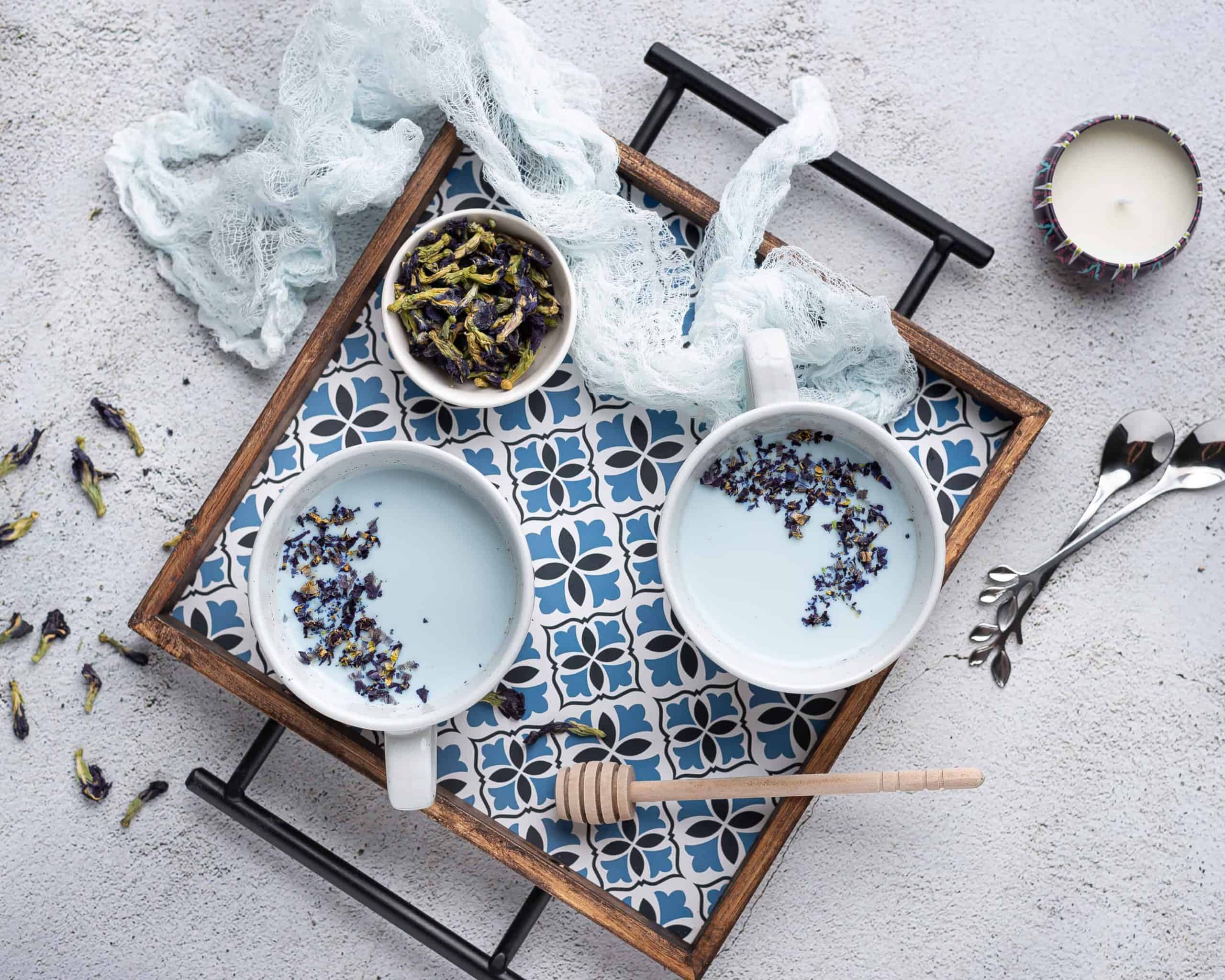 Overhead view of 2 cups of warm blue moon milk on a tray.