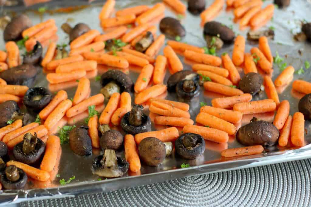 Carrots and mushrooms on a baking sheet.