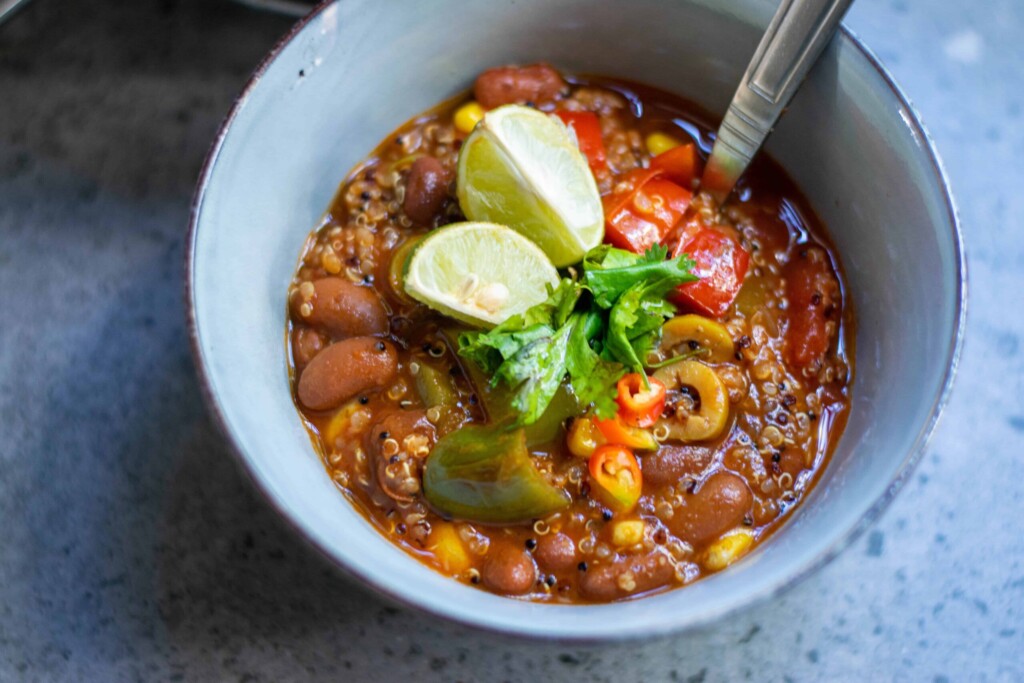 Bowl of vegan chili topped with lime slices and cilantro.
