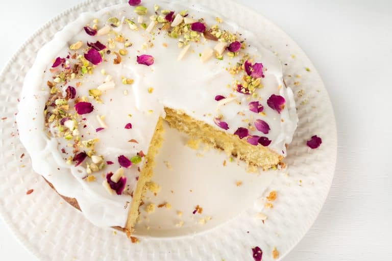 Persian Love Cake on a white plate with a piece cut out of it.