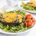 Side view of cheesy mushrooms on greens with cherry tomatoes on the side.