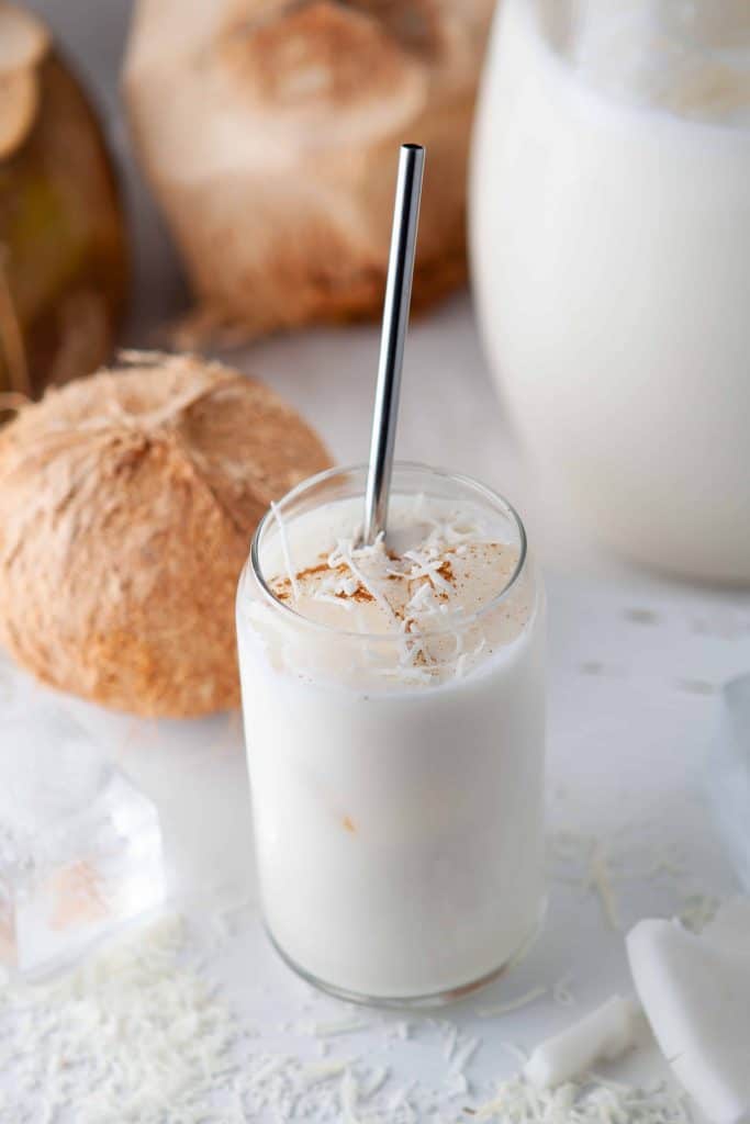 Creamy tropical coconut drink with a stainless steel straw in it.