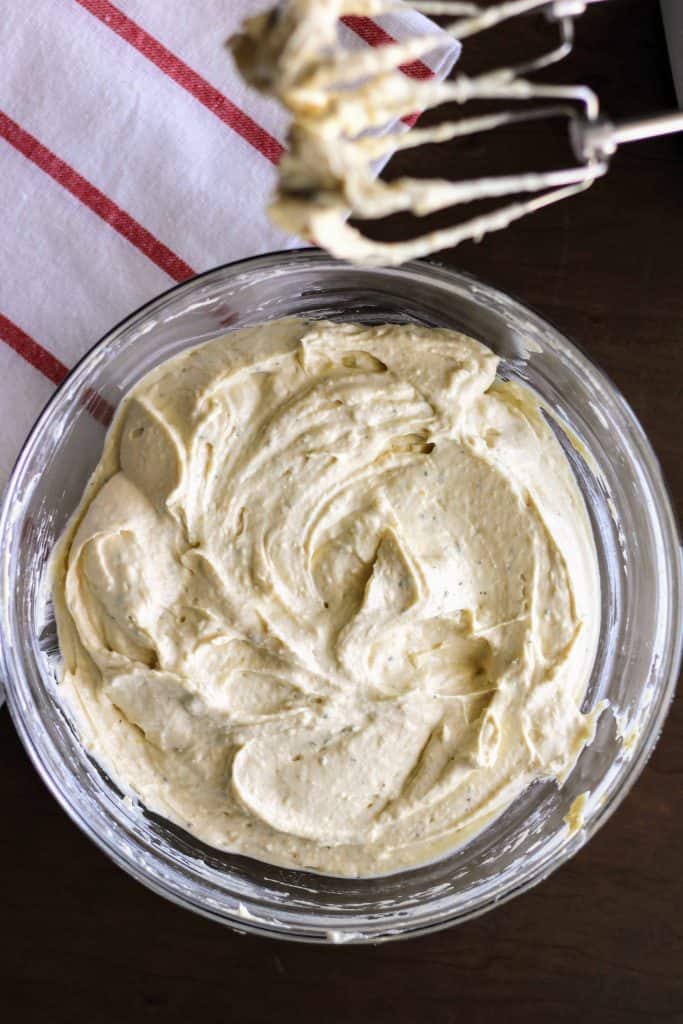 Hummus dip in glass bowl with beaters above it.