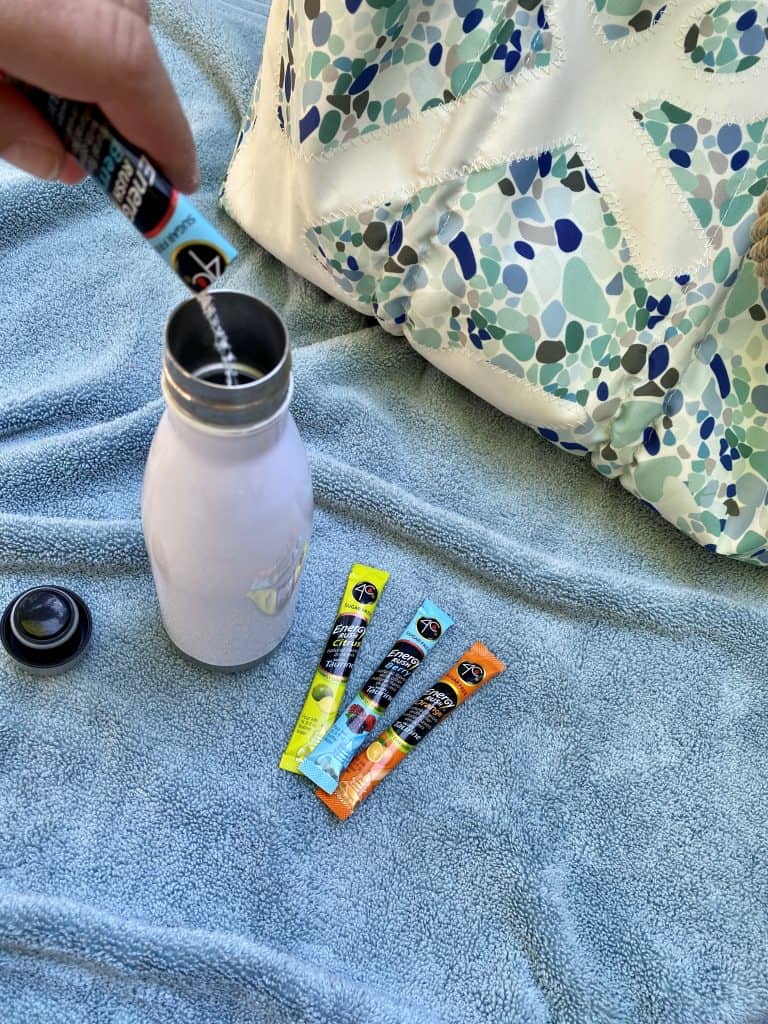 Pouring a packet of drink powder into a water bottle.