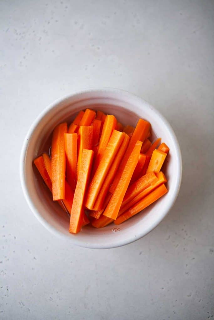 Pickle carrots in a white bowl.