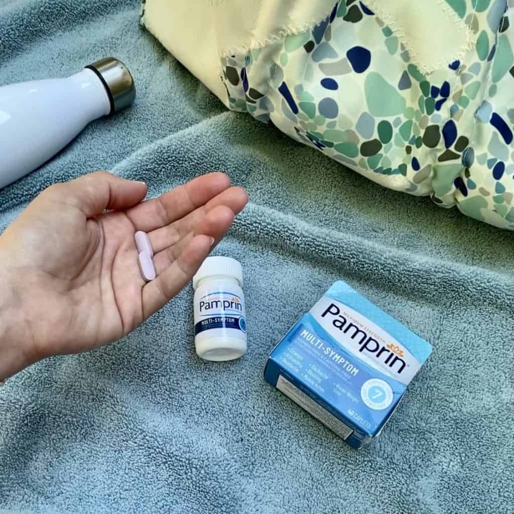 Holding 2 caplets in my hand with Pampering bottle in background.