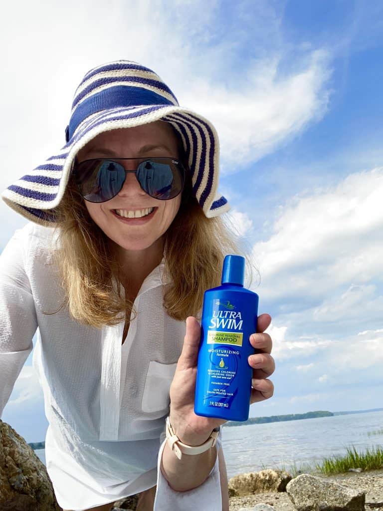 Beautiful lady with beach hat and glasses holding Ultra Swim Shampoo