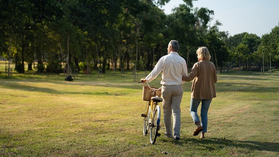 Save Download Preview The behind of Caucasian elderly couples walking with a bicycle in the natural autumn sunlight garden feel cherish and love, concept elderly love, warm family, happy retirement, retirement lifestyle.
